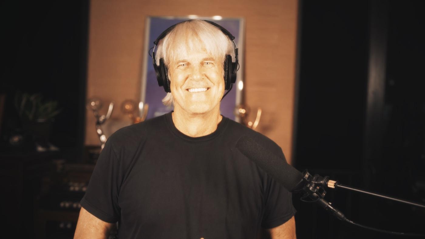 John Tesh wearing headphones while recording audio