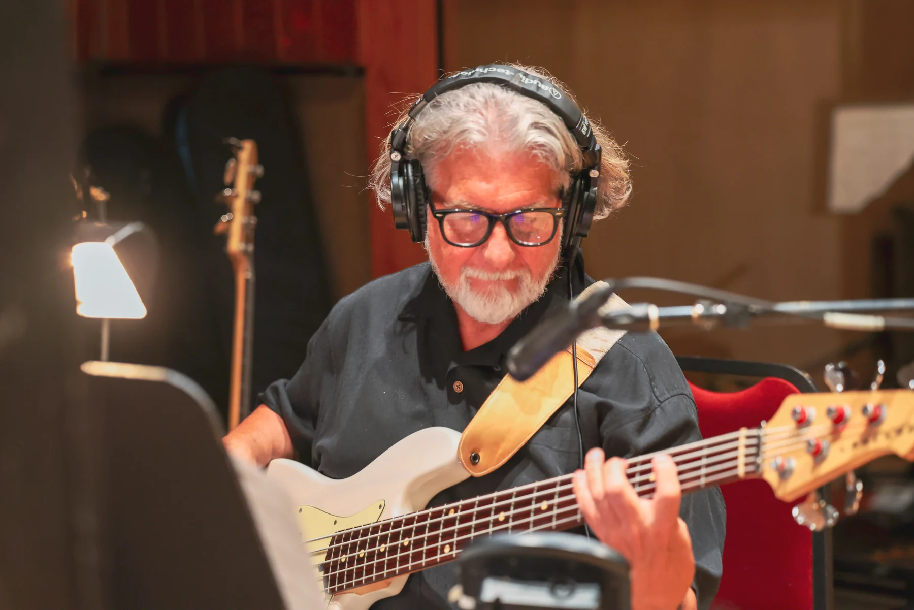 Bass player recording with headphones in the studio